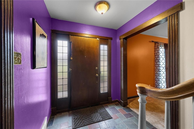 foyer entrance with stone finish floor and baseboards