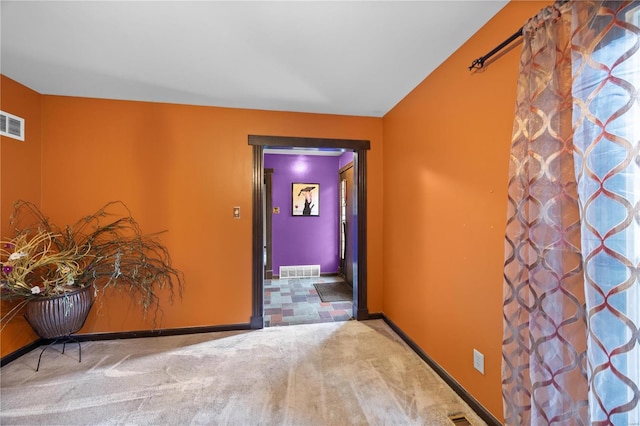 hallway with visible vents, baseboards, and carpet flooring