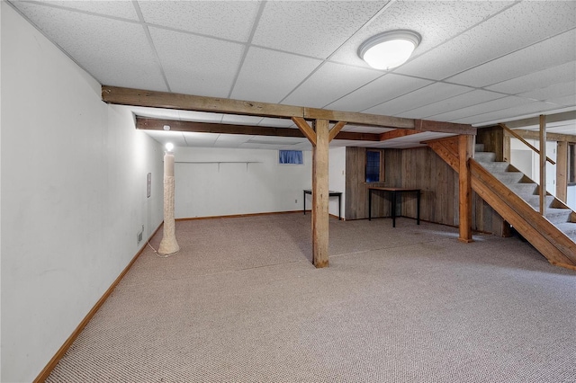 finished below grade area featuring stairway, carpet flooring, a paneled ceiling, and baseboards