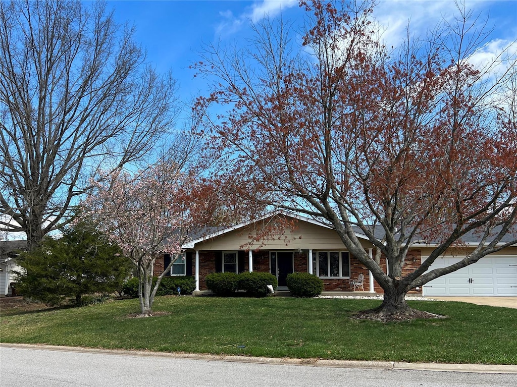 view of front of house featuring an attached garage, driveway, a front lawn, and brick siding