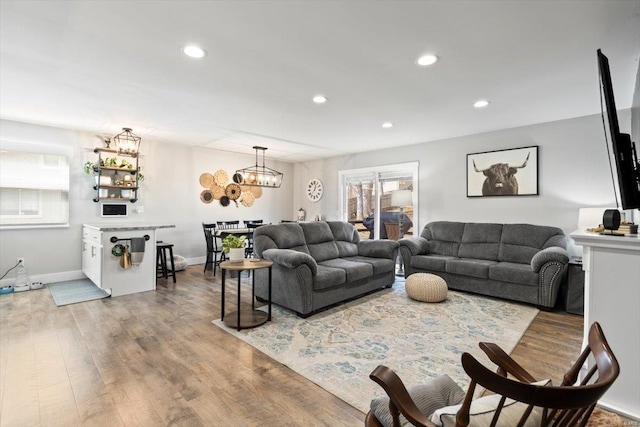 living room with a notable chandelier, recessed lighting, wood finished floors, and baseboards