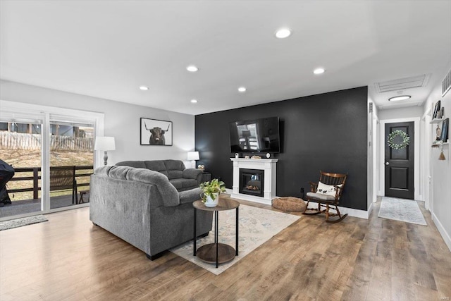 living room with a glass covered fireplace, recessed lighting, baseboards, and wood finished floors