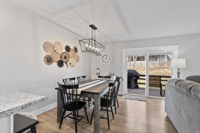 dining room featuring an inviting chandelier, baseboards, and light wood finished floors