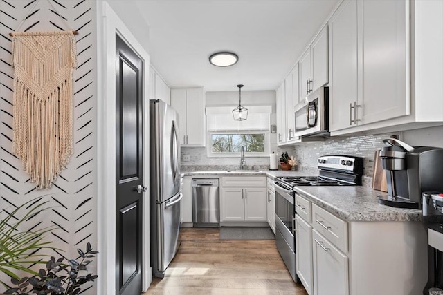 kitchen featuring a sink, stainless steel appliances, white cabinets, and decorative backsplash