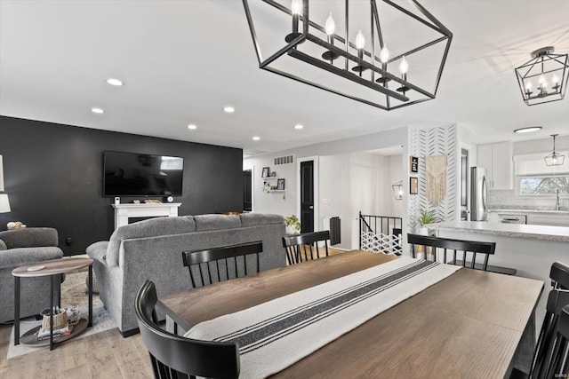 interior space with light wood-style flooring, recessed lighting, visible vents, and a chandelier