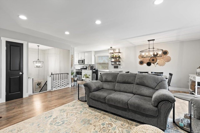 living area with a chandelier, recessed lighting, baseboards, and wood finished floors