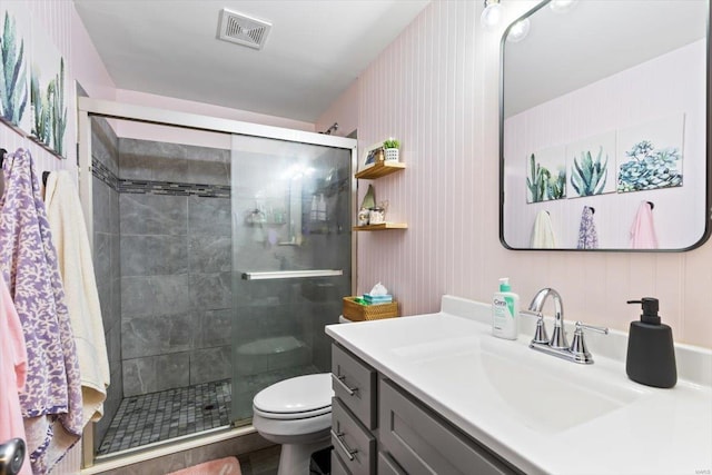 bathroom with visible vents, toilet, a stall shower, and vanity