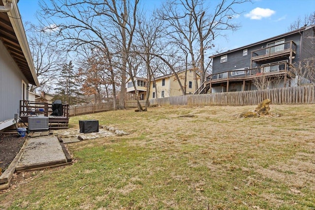 view of yard with central AC unit, a wooden deck, and a fenced backyard