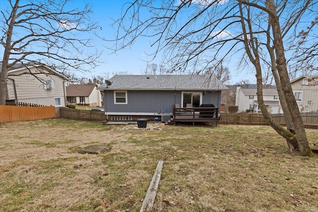 back of property with a lawn, a wooden deck, and a fenced backyard