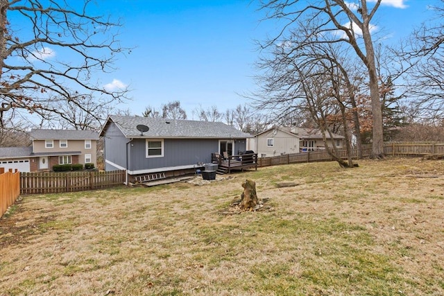 rear view of house featuring a yard, a deck, and a fenced backyard