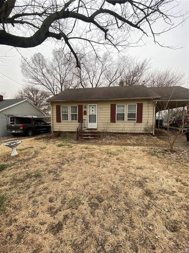 single story home featuring an attached carport, entry steps, and a chimney