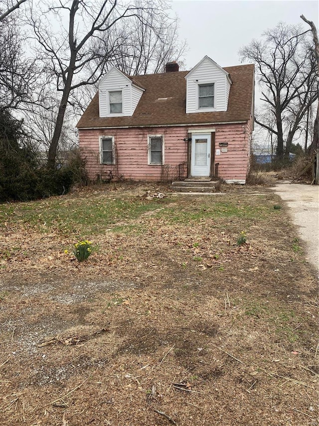 cape cod home with entry steps, roof with shingles, and a chimney