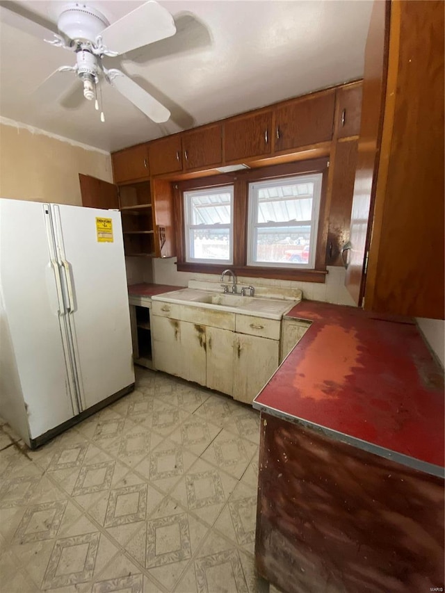 kitchen featuring a sink, light floors, freestanding refrigerator, a ceiling fan, and open shelves