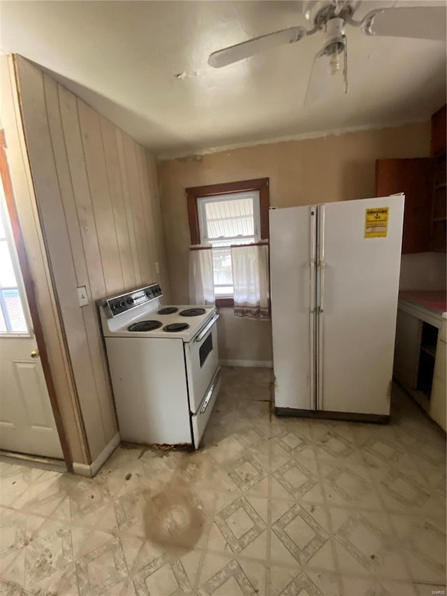 kitchen with white appliances, light floors, wood walls, and a ceiling fan