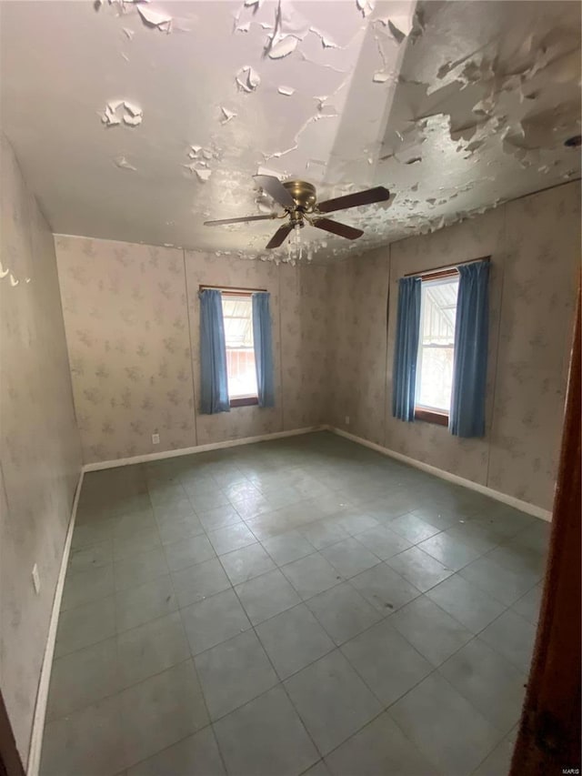 tiled spare room featuring wallpapered walls, baseboards, and ceiling fan