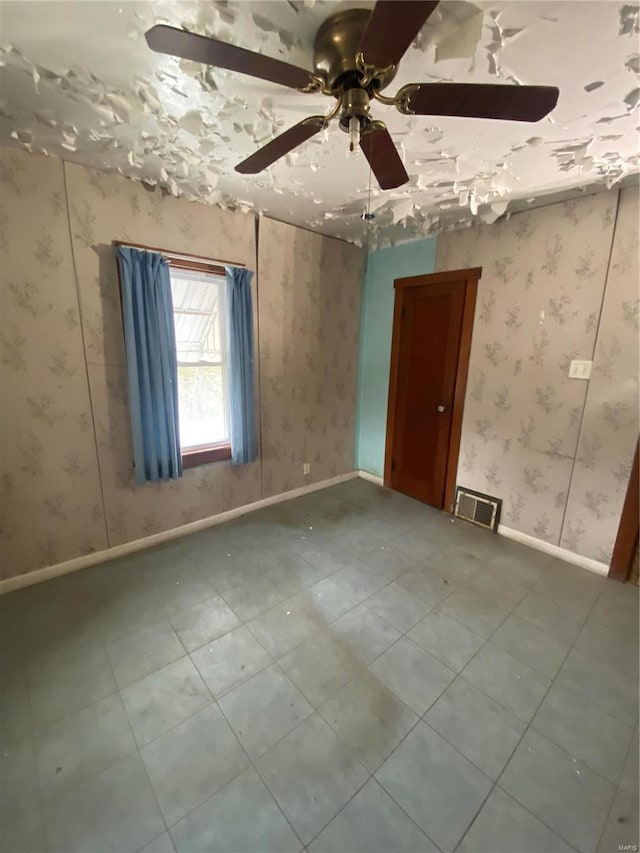 spare room with wallpapered walls, baseboards, visible vents, and ceiling fan