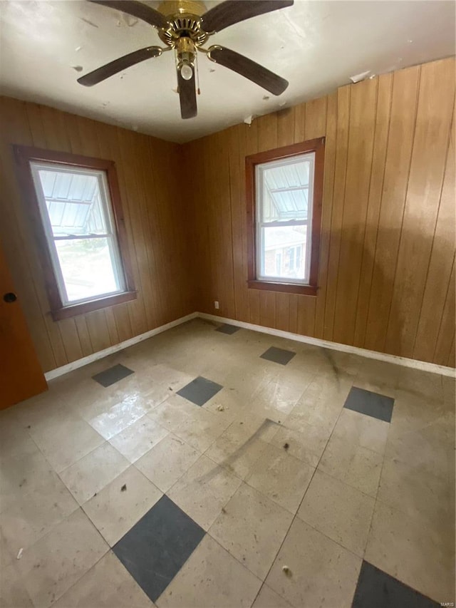 spare room featuring visible vents, wood walls, a ceiling fan, and baseboards