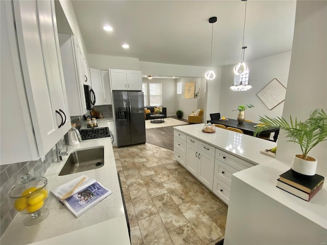 kitchen with black appliances, decorative light fixtures, tasteful backsplash, white cabinetry, and light countertops