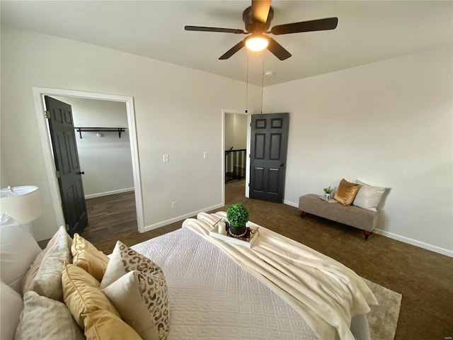 bedroom with a walk in closet, baseboards, ceiling fan, and carpet flooring