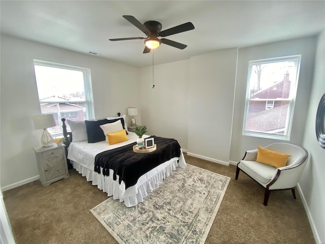 carpeted bedroom with visible vents, multiple windows, a ceiling fan, and baseboards