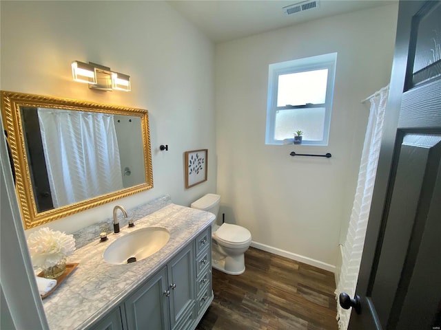 full bath with visible vents, toilet, wood finished floors, baseboards, and vanity