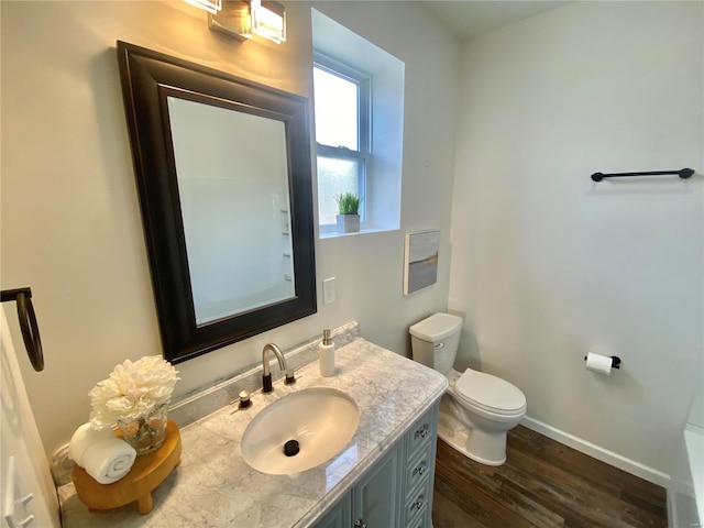 bathroom featuring vanity, toilet, wood finished floors, and baseboards