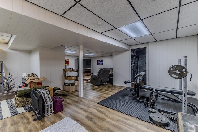 exercise area featuring wood finished floors and a drop ceiling