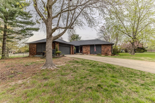 mid-century home with brick siding, a front yard, an attached garage, and driveway