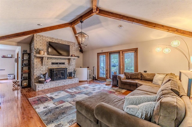 living area featuring baseboards, hardwood / wood-style flooring, a fireplace, a textured ceiling, and vaulted ceiling with beams