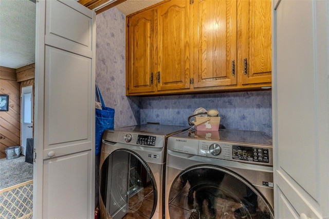 washroom with washer and dryer, a textured ceiling, and cabinet space