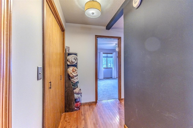 corridor with light wood finished floors and baseboards