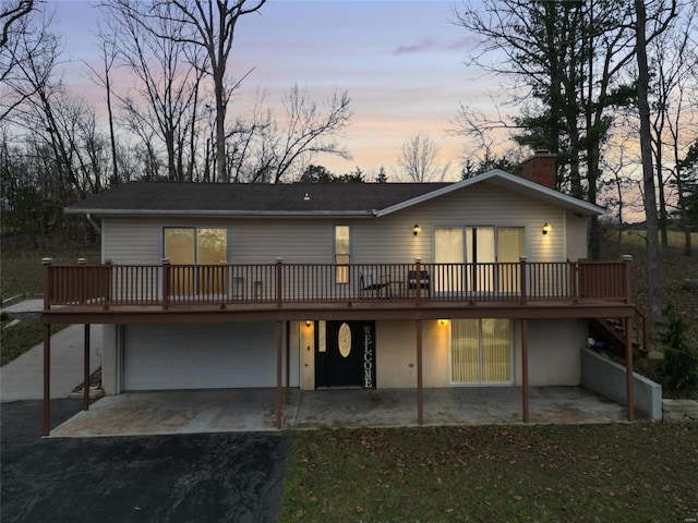 rear view of house featuring aphalt driveway, a patio, a deck, and an attached garage