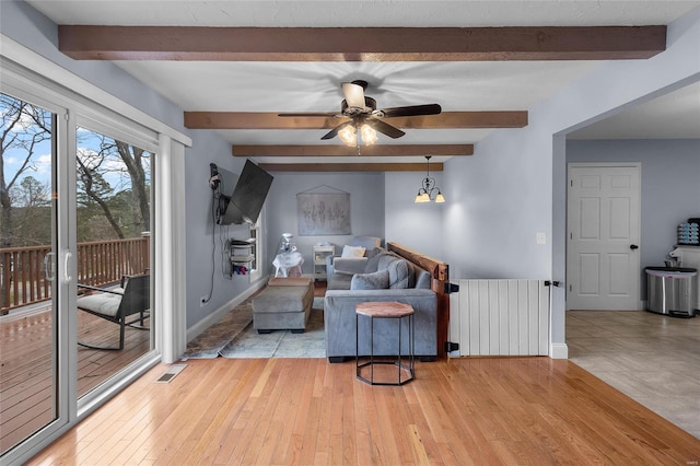 living area featuring visible vents, ceiling fan, light wood-type flooring, radiator heating unit, and beam ceiling