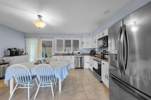 kitchen featuring a sink, stainless steel appliances, white cabinets, and light tile patterned floors