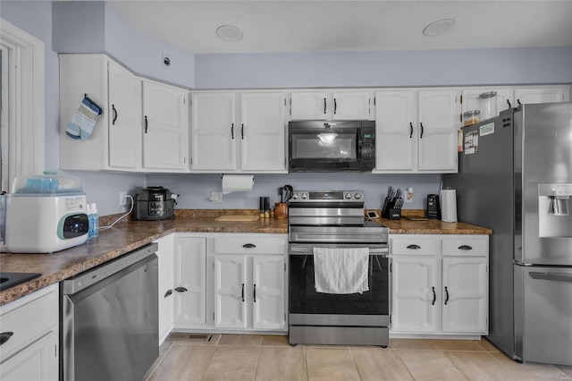 kitchen with white cabinetry, dark countertops, light tile patterned floors, and stainless steel appliances