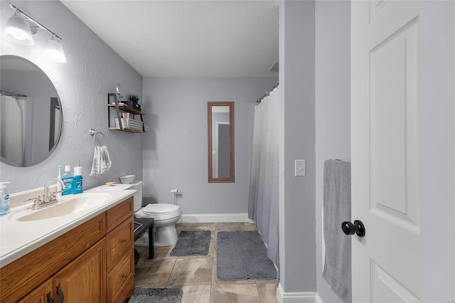 bathroom featuring baseboards, toilet, vanity, and a textured wall