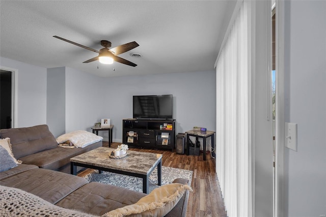 living room featuring visible vents, dark wood-type flooring, ceiling fan, and a textured ceiling