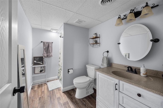 full bath featuring toilet, wood finished floors, visible vents, and a drop ceiling