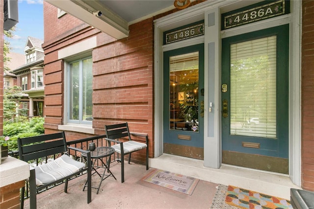 doorway to property with brick siding and a porch