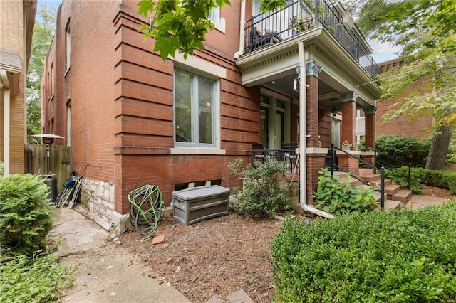 view of property exterior with brick siding, covered porch, and a balcony