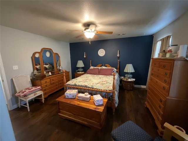 bedroom with a ceiling fan, visible vents, baseboards, and dark wood finished floors