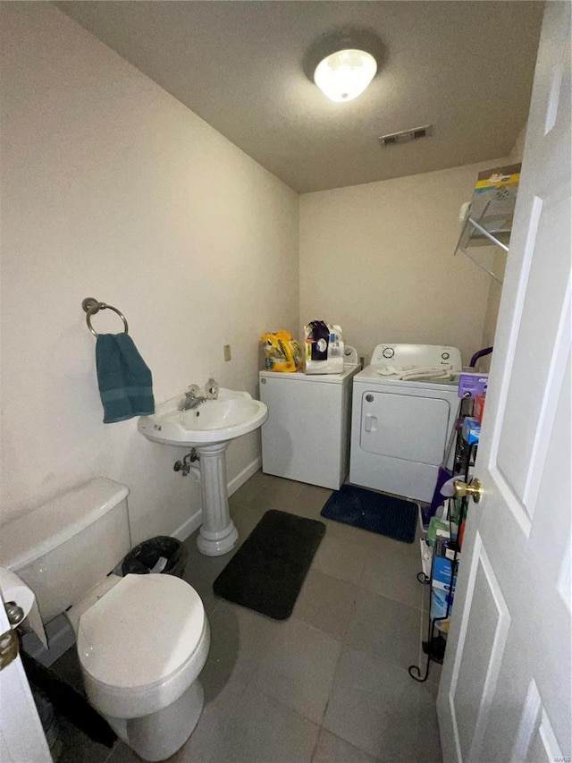half bathroom with tile patterned floors, visible vents, washer and dryer, and toilet
