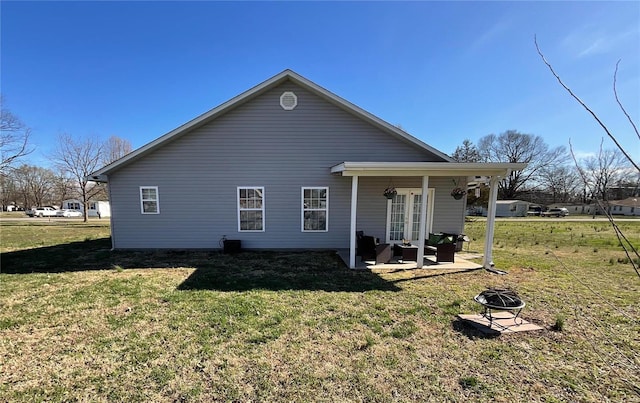 back of house with a fire pit, a patio, french doors, and a yard