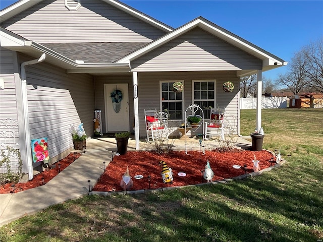 view of front facade featuring covered porch, a shingled roof, and a front yard