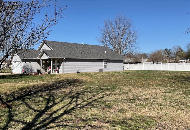 exterior space with a yard, a shingled roof, and fence