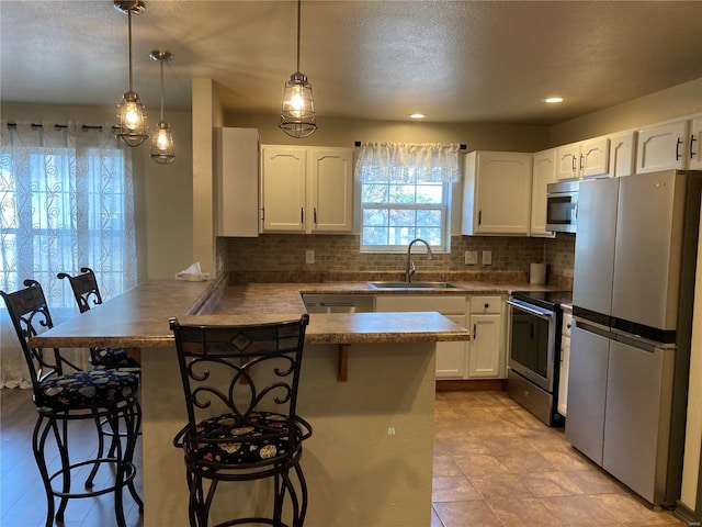 kitchen with a sink, a kitchen bar, appliances with stainless steel finishes, and a peninsula