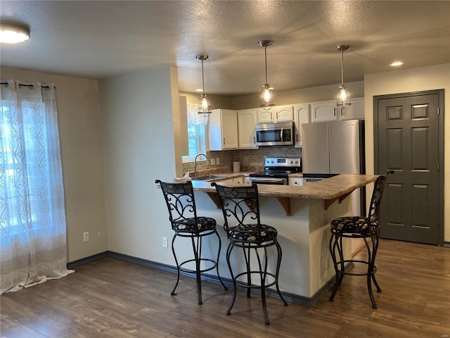 kitchen with a sink, appliances with stainless steel finishes, a peninsula, and a breakfast bar