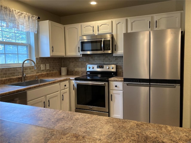 kitchen featuring tasteful backsplash, white cabinets, stainless steel appliances, and a sink