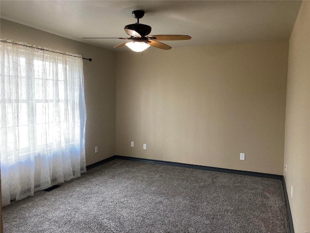 carpeted spare room featuring baseboards and a ceiling fan