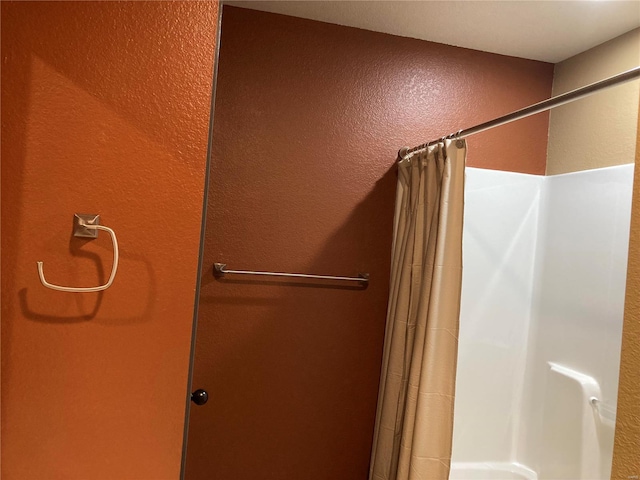 bathroom with a shower with curtain and a textured wall